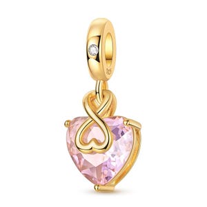 May include: A gold-toned charm featuring a heart-shaped light pink gemstone. The charm includes an infinity symbol loop above the heart and a small clear stone set into the top bail, which is stamped with the text S925 for metal purity.