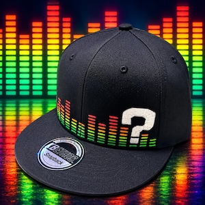 May include: A black snapback cap featuring an embroidered graphic of a colorful sound equalizer bar and a white question mark on the front panel. A circular sticker with the text KB ETHOS Premium Headwear Snapback is on the flat brim.