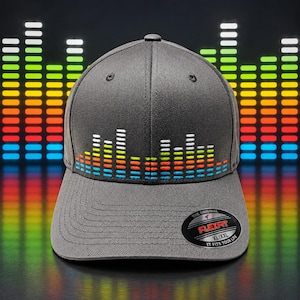 May include: A charcoal gray baseball cap featuring an embroidered multi-colored sound wave graphic across the front panels. The cap includes a circular black sticker on the brim with the text The Original Flexfit XL/XXL It Fits Your Life.