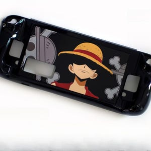 May include: Black protective case for a handheld gaming device. The case features a graphic of a character with a straw hat and a skull and crossbones on a black background. The case is designed to fit the device.