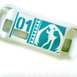 Może przedstawiać: Białe etui ochronne na przenośną konsolę do gier. Etui posiada turkusową grafikę postaci z długimi kucykami, numer "01" i geometryczne kształty. Etui posiada wycięcia na przyciski i porty.