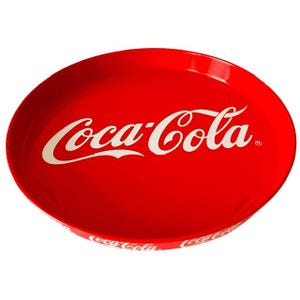 Könnte beinhalten: Ein rundes, leuchtend rotes Serviertablett mit dem weißen Coca-Cola-Logo in der Mitte. Das Tablett hat einen erhöhten Rand, auf dessen Außenseite der Markenname Coca-Cola wiederholt in weißer Schrift aufgedruckt ist, was ein einheitliches Design ergibt.
