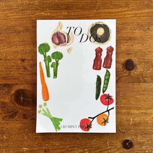 May include: A white notepad with the text TO DOs at the top and CRUMPET PRINTS at the bottom. The border features illustrations of garlic, a mushroom, broccoli, a carrot, green onions, two red pepper mills, a green bean, and red and orange tomatoes.