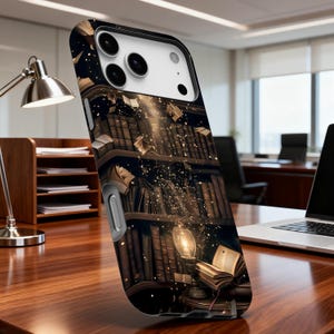 May include: A phone case featuring a detailed illustration of a library with floating books and a glowing light. The design is predominantly brown and gold, creating a warm and inviting aesthetic. The case is on a wooden desk.