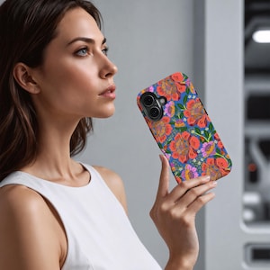 May include: A floral phone case featuring a vibrant pattern of orange, red, and purple flowers on a blue background. The case has a sleek design and is held by a person.