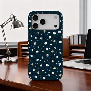 Pode incluir: Uma capa de telemóvel azul marinho com um padrão floral branco e amarelo. A capa tem um acabamento mate e foi concebida para um smartphone. O design floral é composto por pequenas flores semelhantes a margaridas e pontos brancos.