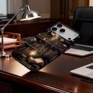 May include: A black phone case featuring a detailed illustration of a library with books, a glowing light, and floating books. The case has a glossy finish and is designed for a smartphone. The case is on a wooden desk.