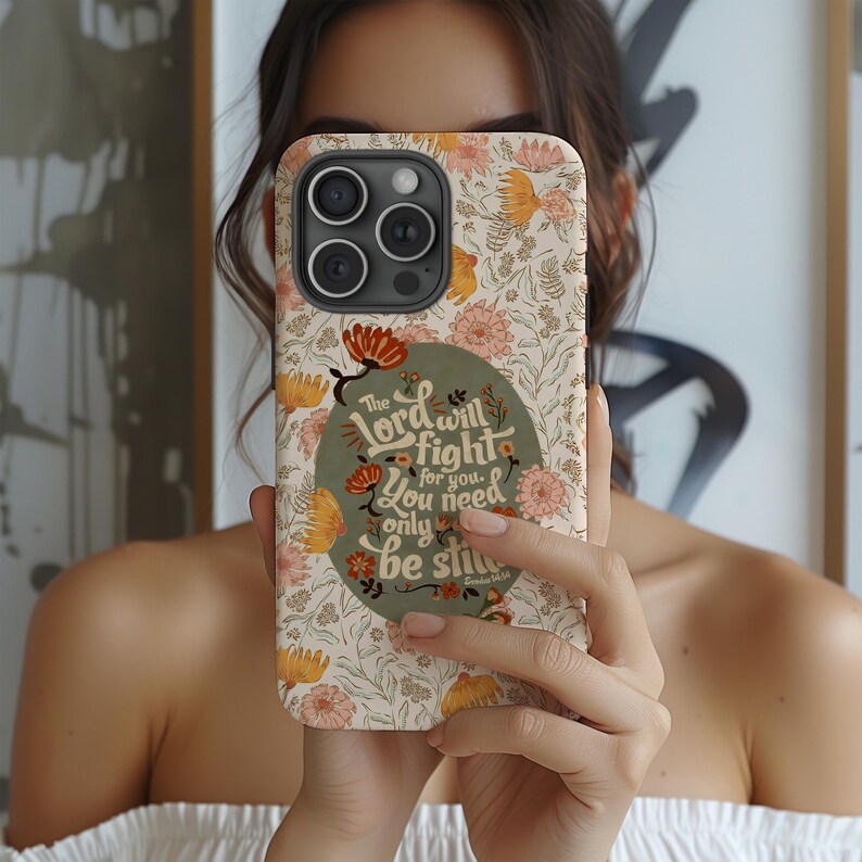 May include: A floral phone case with a cream background and orange, pink, and yellow flowers. The case features the text "The Lord will fight for you. You need only be still."