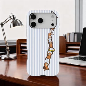 Puede incluir: Funda de teléfono a rayas blancas y azules claras con una ilustración lúdica de monos marrones colgados unos de otros. Un mono sostiene un plátano. La funda tiene un recorte para la cámara.
