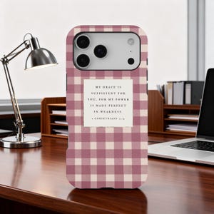 Puede incluir: Una funda de teléfono con un patrón de cuadros rosa y blanco. La funda tiene una etiqueta rectangular blanca con el texto "MY GRACE IS SUFFICIENT FOR YOU, FOR MY POWER IS MADE PERFECT IN WEAKNESS. 2 CORINTHIANS 12:9."