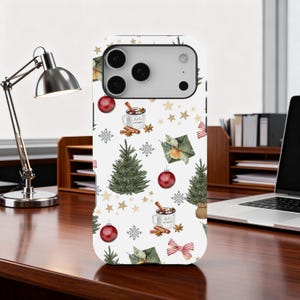 Puede incluir: Una funda blanca para teléfono con un diseño navideño festivo. El diseño incluye árboles de Navidad verdes, adornos rojos, estrellas doradas, copos de nieve y regalos envueltos. La funda también presenta una taza con el texto "Hello Winter".