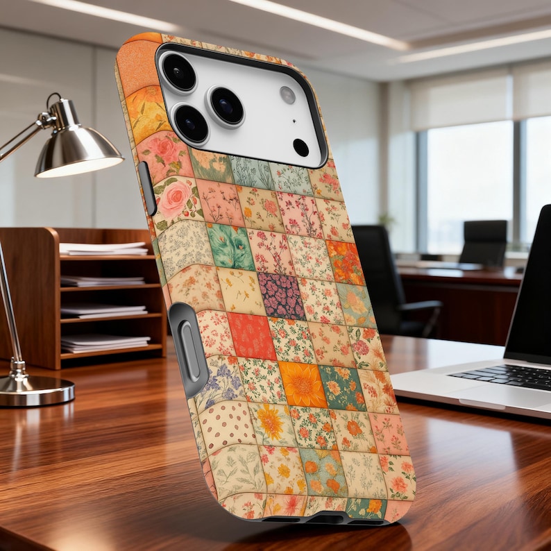 May include: A colorful phone case with a patchwork design. The case features a variety of floral patterns in squares of various colors, including pink, green, orange, and yellow. The case is designed to fit a smartphone and has a black side.