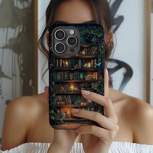 May include: A phone case featuring a detailed illustration of a bookshelf filled with books, candles, and decorative items. The design includes a dark, moody color palette with hints of green and blue, creating a cozy, fantasy aesthetic.