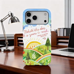 May include: A phone case with a colorful landscape design. The case features a vibrant sunrise over rolling green hills, a rainbow, and a quote that reads, "Behold this day, it is yours to make." The quote is attributed to American Indian Proverbs.