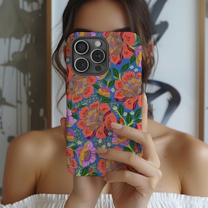 May include: A floral phone case featuring a vibrant pattern of orange, pink, and yellow flowers on a blue background. The case has a glossy finish and a camera cutout.
