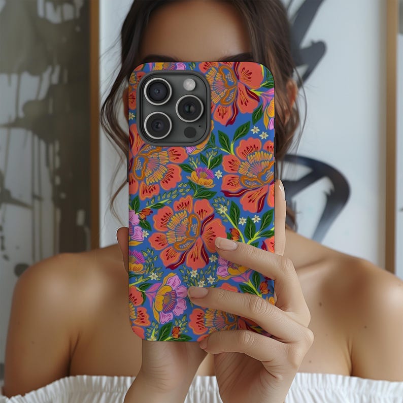 May include: A floral phone case featuring a vibrant pattern of orange, pink, and yellow flowers on a blue background. The case has a glossy finish and a camera cutout.