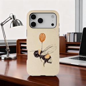 Puede incluir: Funda de teléfono beige con una ilustración en acuarela de un abejorro sosteniendo un pequeño globo naranja. La abeja tiene rayas negras y amarillas y alas detalladas. La funda tiene un recorte para la cámara y ubicaciones de botones.