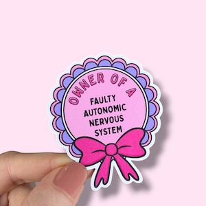 Könnte beinhalten: Ein rosa Aufkleber mit dem Text "OWNER OF A FAULTY AUTONOMIC NERVOUS SYSTEM". Der Aufkleber hat einen gewellten Rand in Lila und eine rosa Schleife unten. Der Hintergrund ist einfarbig hellrosa.