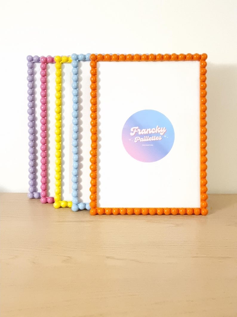 May include: A stack of colorful picture frames with rounded edges. The frames are in shades of purple, pink, yellow, blue, and orange. Each frame has a white interior. The orange frame has a sticker with the text "Francky Paillettes".