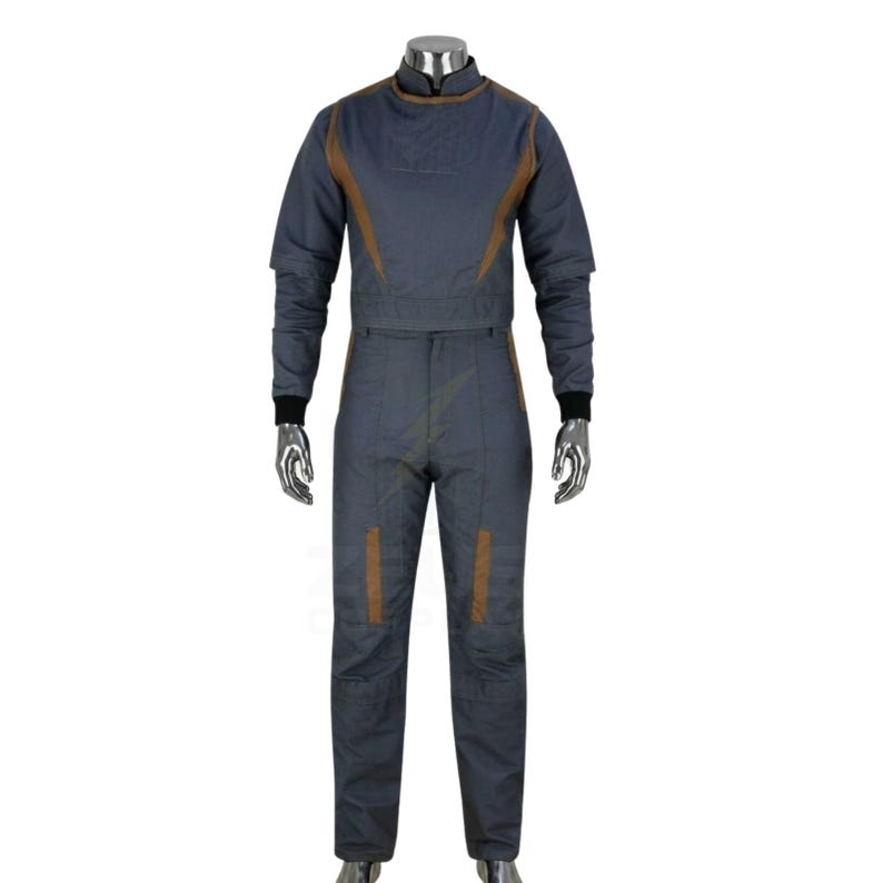 May include: A gray jumpsuit with brown accents. The long-sleeved top has a high collar and brown trim along the shoulders and chest. The pants have brown patches on the legs. Black cuffs are at the wrists and ankles.
