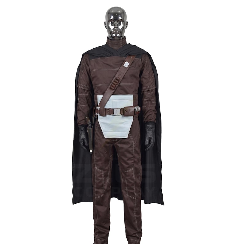 May include: A brown costume with a black cape, gloves, and a utility belt. The costume includes a brown jumpsuit, a white midsection, and a brown shoulder strap. The mannequin has a silver head.