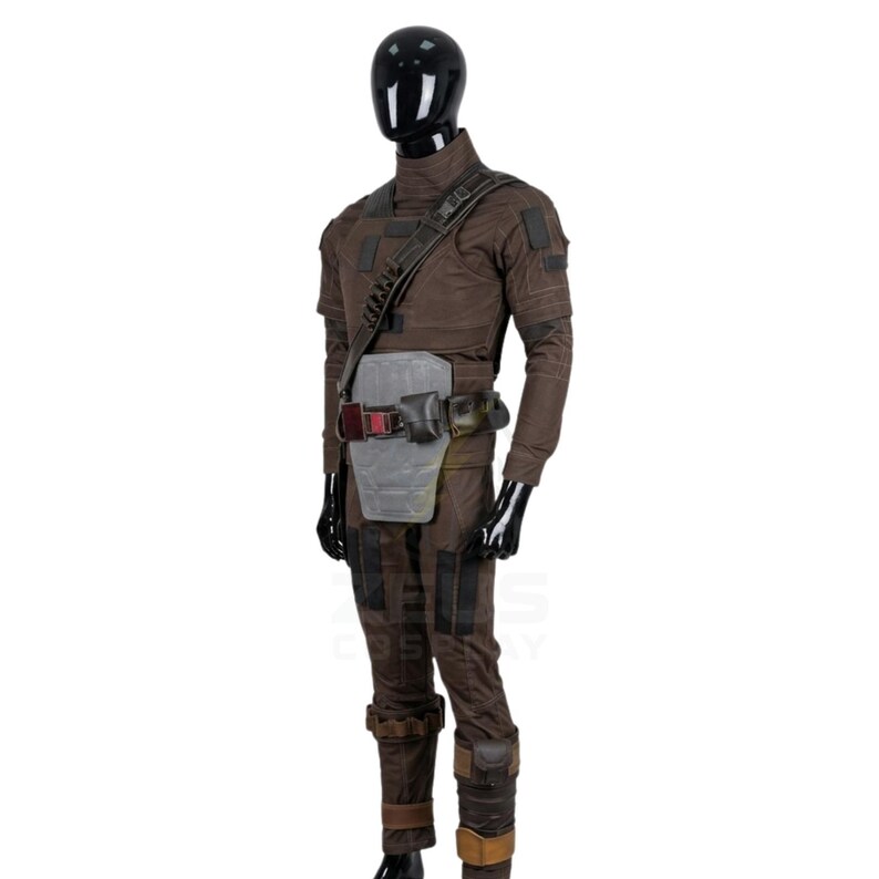 May include: A brown tactical jumpsuit featuring a high collar, long sleeves, and reinforced patches. The outfit includes a dark diagonal shoulder strap, a light gray abdominal plate, and a utility belt with attached pouches and dark hardware.