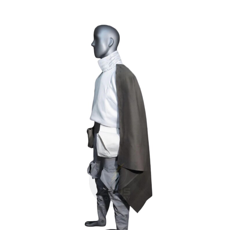 以下が含まれることがあります： 白いハイネックのチュニック、グレーのパンツ、肩にかけられたダークグレーのマントが特徴のコスチューム。この衣装には、ユーティリティベルトとポーチが含まれています。マネキンは白い背景に設定されています。