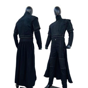 Pode incluir: Dois conjuntos pretos exibidos em manequins. Os conjuntos apresentam uma jaqueta de gola alta com costuras contrastantes, mangas compridas e uma saia longa ou cal&ccedil;as a condizer. As jaquetas t&ecirc;m cintura ajustada e as cal&ccedil;as t&ecirc;m detalhes nos joelhos.