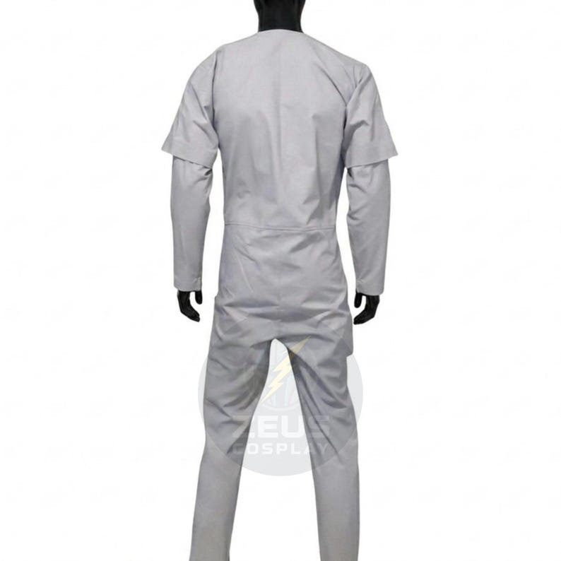 May include: A light gray jumpsuit with long sleeves and a round neckline. The jumpsuit has a fitted silhouette and a zipper closure. The model is wearing black gloves. The jumpsuit is made of a lightweight fabric.