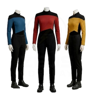 Puede incluir: Tres conjuntos de uniforme sobre maniquíes, cada uno con pantalones negros y una camiseta de manga larga con cuello alto. Las camisetas tienen mangas y paneles laterales negros con un panel frontal azul, rojo o dorado en el pecho.