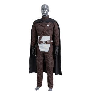 May include: A brown costume with a black cape, gloves, and a belt with a silver buckle. The costume includes a long-sleeved top, pants, and a white panel on the front. A mannequin displays the outfit.