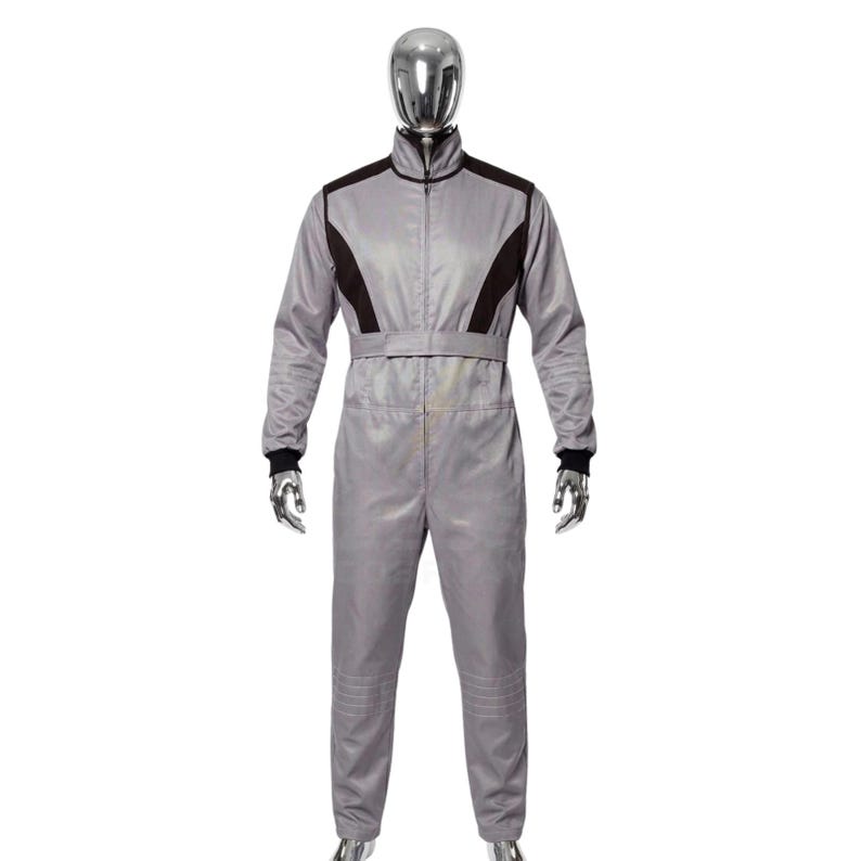 May include: A gray racing suit with black accents on the shoulders and chest. The suit has a zip-up front, a belt, and black cuffs at the wrists. The mannequin is wearing the one-piece garment.
