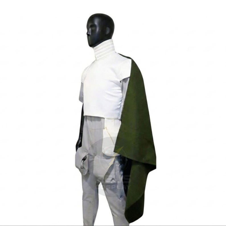 May include: A costume featuring a white top with a high collar, a dark green cape, and light gray pants. The outfit is displayed on a mannequin against a white background. The costume has a futuristic or fantasy theme.