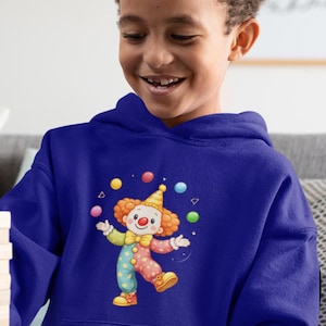 Puede incluir: Una sudadera con capucha azul real con un payaso de dibujos animados que hace malabarismos con pelotas. El payaso tiene pelo naranja, un sombrero amarillo y un atuendo de lunares. El diseño está centrado en la parte delantera de la sudadera, adecuado para ropa infantil.