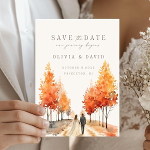 May include: A rectangular Save the Date card featuring a watercolor illustration of a couple walking down a path lined with vibrant orange and yellow autumn trees. The text reads: SAVE THE DATE, our journey begins, OLIVIA & DAVID, OCTOBER 3.20XX, PRINCETON, NJ.