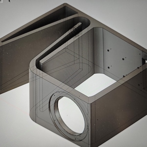 Puede incluir: Una representación 3D de un diseño de caja de altavoz. El diseño presenta una caja rectangular con una abertura circular y una estructura en forma de bocina en ángulo. El modelo está renderizado en tonos grises, mostrando la estructura interna.