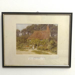 May include: Framed print of a cottage scene. The artwork depicts a cottage with a red tile roof, surrounded by lush greenery. The print is in a black frame with a gold inner border. The text at the bottom reads "A British Cottage by Helen Allingham, R.W.S. 1848-1926."