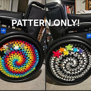 Op de afbeelding: Twee rolstoelwielen met gehaakte hoezen. Eén wielhoes is een spiraal van regenboogkleuren, de andere is zwart, wit en grijs. De tekst "PATTERN ONLY!" staat bovenaan.