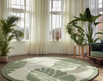 May include: A round area rug featuring a cream-colored base with large, embossed green monstera leaf patterns and a solid green border. The text EarthLoomRugs is printed in small white letters on the surface of the rug.