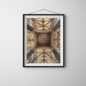 May include: A framed print of a cathedral ceiling, displaying detailed architecture. The image shows a vaulted ceiling with ribbed arches, stained glass windows, and a central decorative panel. The color scheme features beige and brown hues.