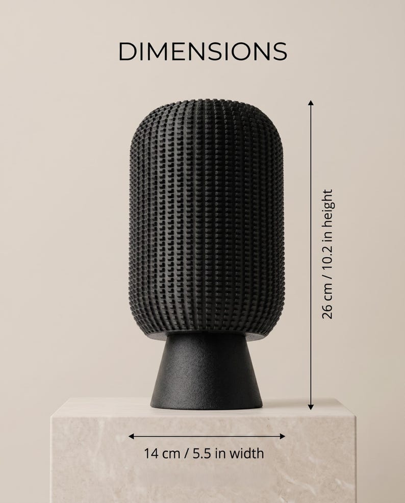 K&ouml;nnte beinhalten: Eine schwarze Vase mit einer texturierten, gitterartigen Oberfl&auml;che und einem glatten, konischen Fu&szlig;. Das Objekt ist mit Ma&szlig;en von 26 cm H&ouml;he und 14 cm Breite versehen. Der Text DIMENSIONS steht oben im Bild.