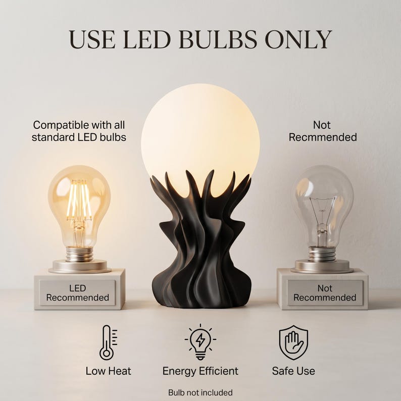 May include: A black sculptural table lamp with a frosted globe shade. The lamp is flanked by two light bulbs, one LED and one incandescent, with text indicating LED bulbs are recommended. The image includes text: "USE LED BULBS ONLY".