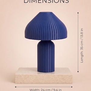 May include: A dark blue mushroom-shaped lamp with a vertically ribbed texture. The lamp stands on a rectangular beige base. Text indicates dimensions of 35 cm / 13.8 in in length and 24 cm / 9.4 in in width. The word DIMENSIONS is at the top.
