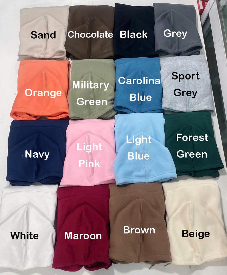 May include: A collection of fleece neck gaiters in various colors, including sand, chocolate, black, grey, orange, military green, Carolina blue, sport grey, navy, light pink, light blue, forest green, white, maroon, brown, and beige. Each gaiter is folded and labeled with its color.