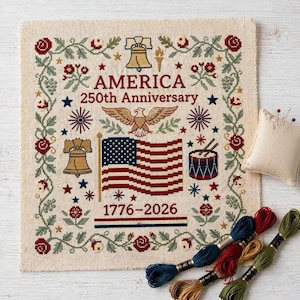 Op de afbeelding: Een kruissteek sampler ter ere van de 250e verjaardag van Amerika, met de Amerikaanse vlag, een adelaar en de Liberty Bell. Het ontwerp bevat rode, witte en blauwe elementen, omringd door bloemen- en stermotieven. Borduurgaren in diverse kleuren inbegrepen.