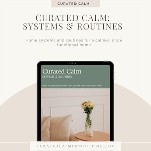 May include: A digital tablet displaying a document titled Curated Calm: Systems & Routines, featuring text about home systems and routines. The screen shows a photograph of a glass vase with white flowers on a wooden table next to beige pillows.