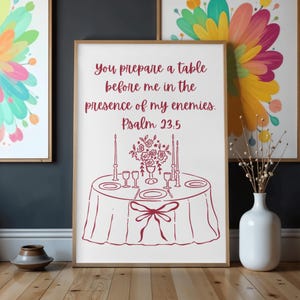 Op de afbeelding: Een ingelijste print met een rode lijntekening van een tafelsetting, inclusief borden, glazen en kaarsen. De tekst "You prepare a table before me in the presence of my enemies. Psalm 23:5" is in rode letters geschreven.
