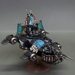 May include: A black miniature sci-fi aircraft featuring a central cockpit with a pilot, a front-mounted turret with a gunner, and a decorative rear shrine with a blue statue. The vehicle has teal wings, metallic gold accents, and blue stained-glass details.