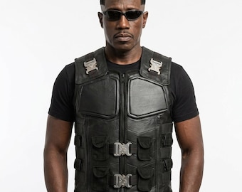 May include: A black tactical vest featuring a front zipper closure, padded chest panels, and multiple utility pockets. The vest is secured with silver-toned metal quick-release buckles on the shoulders and across the front torso area.