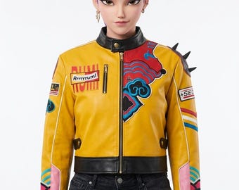 May include: A yellow faux leather jacket with black trim, a high collar, and a front zipper. The jacket features colorful embroidered patches, including one with the text Rrrryruml, and black spikes on the shoulder. It is worn over black jeans.